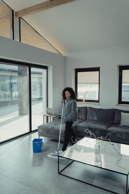 A light blue dustpan and a wooden-handled brush with beige bristles hanging on a white textured wall, arranged with the dustpan facing downward and the brush resting inside it. The scene is evenly lit